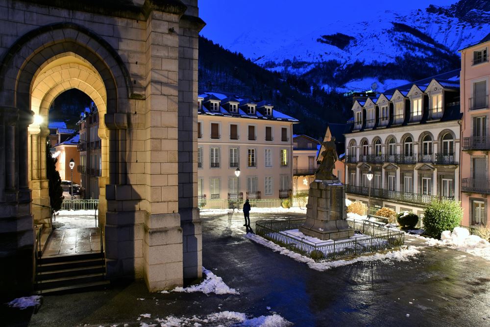 Les bâtiments de style Belle Époque ainsi que l'église de la ville de Cauterets, cernée par les montagnes, de nuit