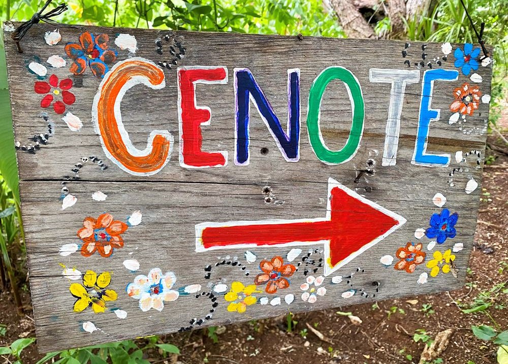 La végétation et le panneau directionnel local indiquant le chemin menant à l'entrée du cénote Kikil.