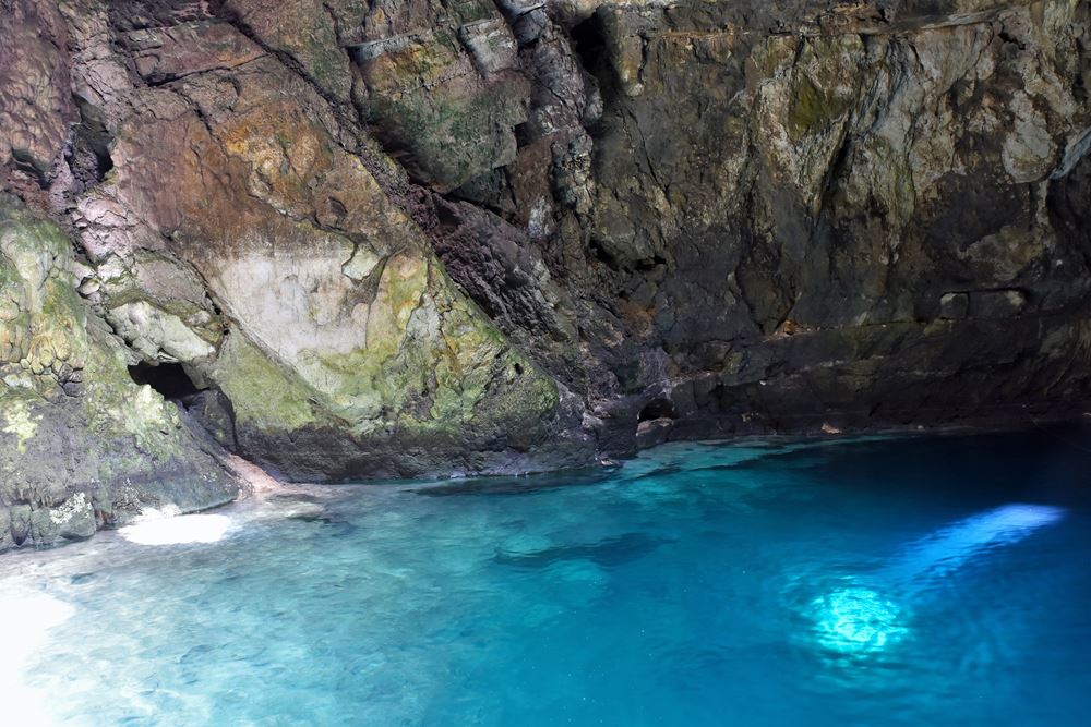 Les rayons du soleil plongent dans l'eau du cénote X'ux Ha en passant à travers son plafond troué.