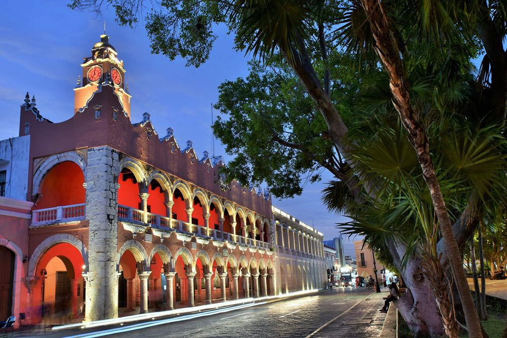 Mérida : la palais municipal, avec ses arcades caractéristiques, s'illumine à la tombée de la nuit, en face du zocalo (plaza grande ou place centrale)