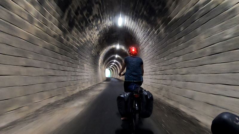 Une cycliste dans un ancien tunnel ferroviaire transformé en piste cyclable sur la piste Lapébie