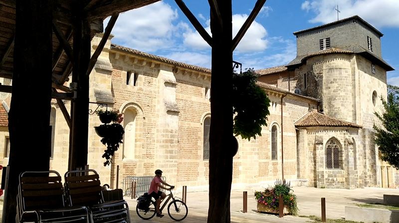 Une cycliste devant l'église Saint-Vincent du Mas-d'Agenais, sur l'itinéraire du canal des Deux-Mers à vélo