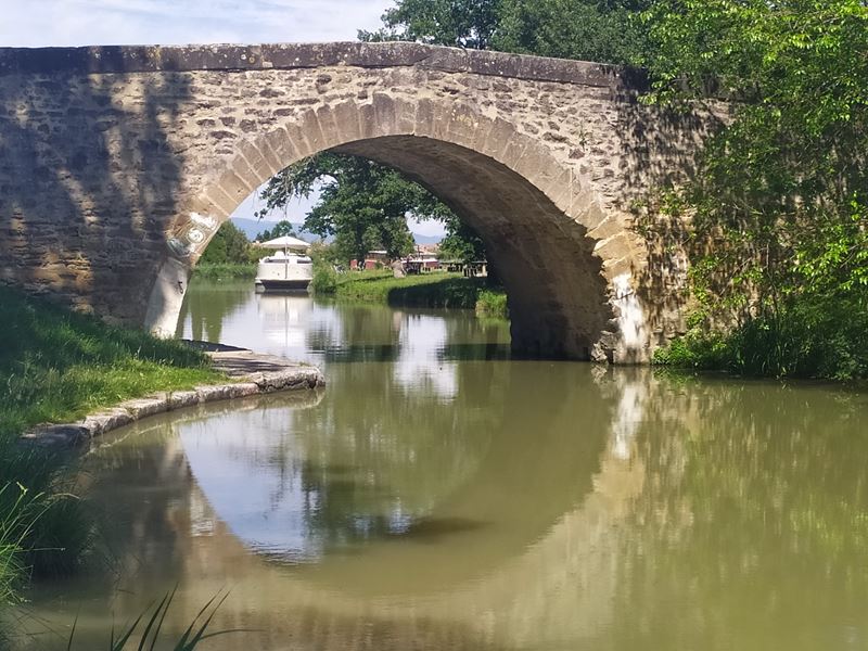 Un petit pont en pierres enjambe le canal du Midi