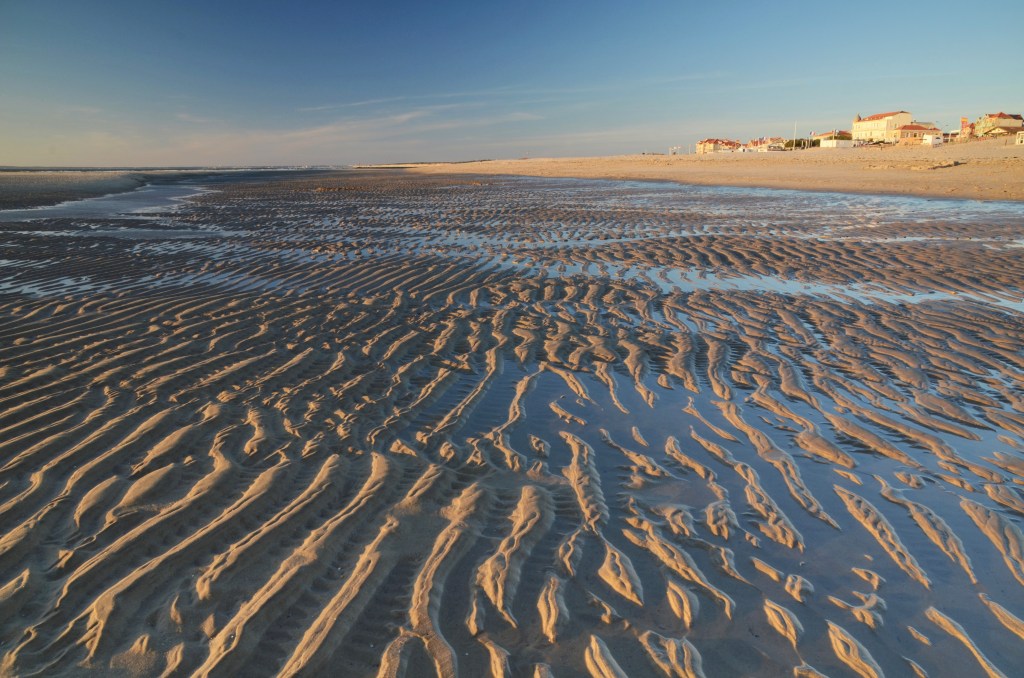 La petite station balnéaire de Soulac-sur-Mer, éclairée par le soleil couchant, domine la plage à marée basse face à l'océan Atlantique