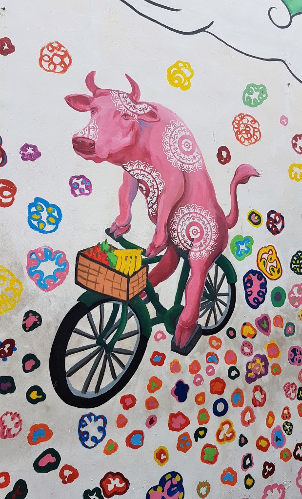 Street-art à Singapour, représentant une vache à vélo et des fleurs