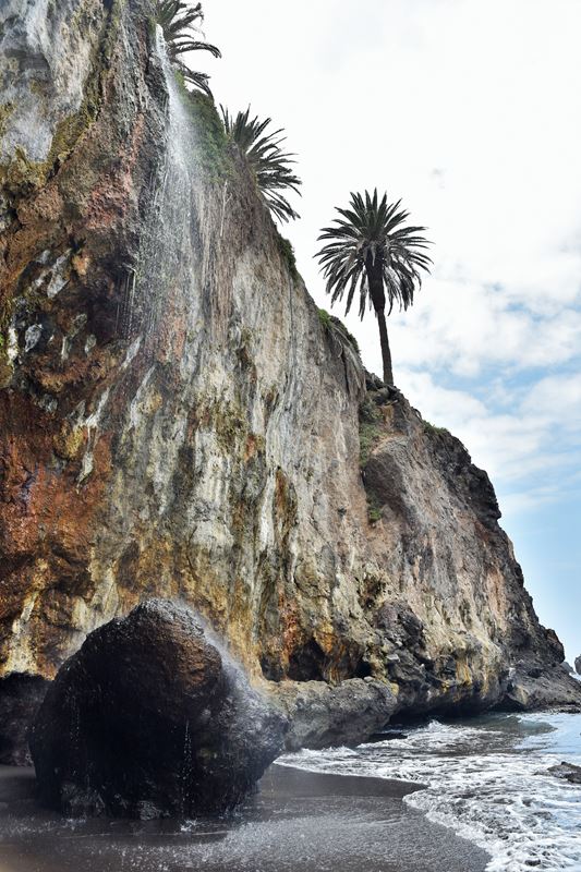 La cascade de la Playa de Castro tombe de la falaise sur un rocher posé sur la plage