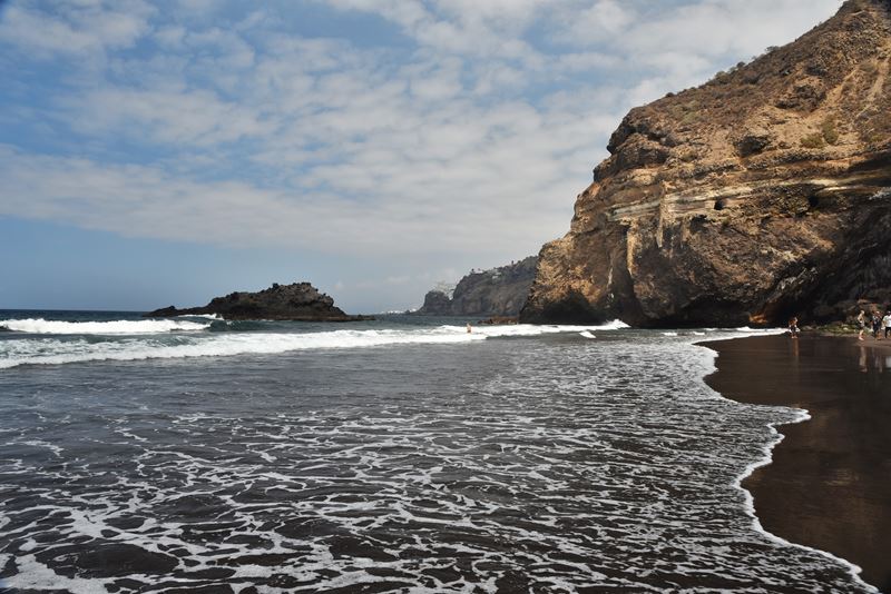 La Playa de Castro, son sable volcanique noir, les vagues de l'océan et la falaise