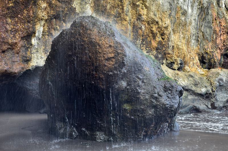 La cascade de la Playa de Castro tombe sur un rocher posé sur la plage