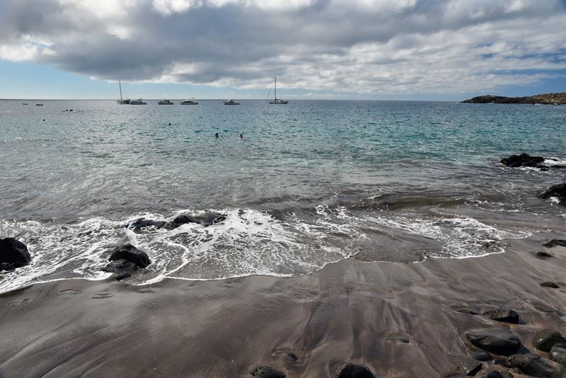 La Playa los Enojados, son sable volcanique noir, la mer et des bateaux
