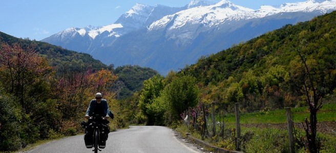 Voyageur à vélo dans un paysage de montagnes enneigées et d'arbres fleuris